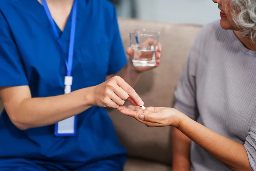 caregiver giving pills to woman