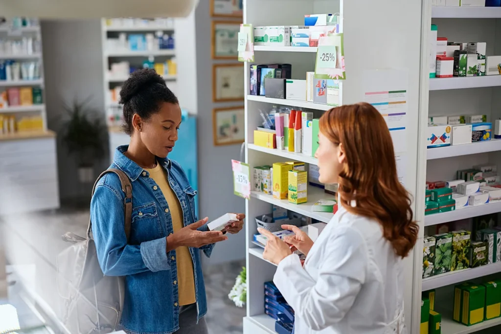 woman speaking with pharmacist inside modern pharm